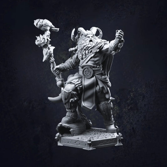 A detailed miniature of a barbarian warrior, featuring a bearded figure wearing a horned helmet. The barbarian wields a staff topped with a bird and is dressed in rugged attire, including fur-lined boots and a belt with a circular emblem. The figure stands on a textured base, exuding a dynamic and imposing presence.