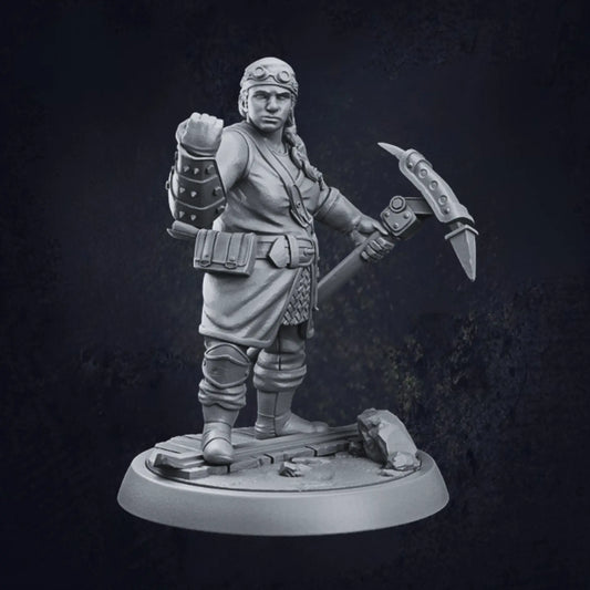 A detailed 3D-printed miniature of a female dwarven artificer, standing on a rocky circular base. The artificer is adorned in a tunic with a belt holding various pouches, paired with armored gauntlets and boots. She wields a large hammer or pickaxe in her right hand, while her left hand is raised in a clenched fist. The model showcases intricate craftsmanship, highlighting the artificer's robust and industrious character.