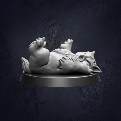A white ceramic figurine of a cat lying on its back on a black base against a dark background.