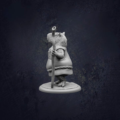 A statue of a mouse holding a stick and standing on a platform against a dark background.