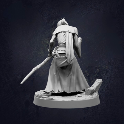 A statue of a person holding a weapon and wearing a long robe, standing on a base against a dark background.