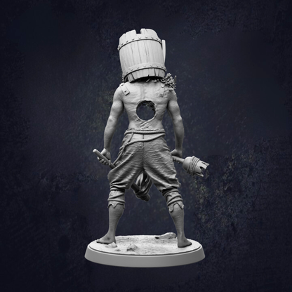 A statue of a person with a barrel on their head, standing on a base and holding a weapon.