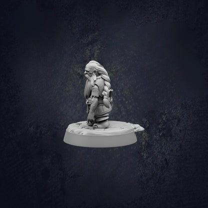 A small, detailed figurine of a person sitting on a platform against a dark background.