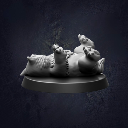 A white figurine of a cat lying on its back on a black base against a dark background.