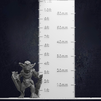 A small figurine of a creature, possibly a monster or a gnome, standing next to a ruler for size comparison.