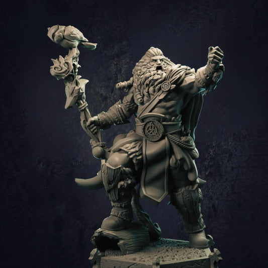 A meticulously crafted miniature figure of a barbarian Viking warrior standing on a rugged, rocky base. The character boasts a powerful, muscular physique, with wild, flowing hair and a full beard. Adorned in traditional Viking attire, the warrior's belt features a prominent circular emblem. He wields a striking staff crowned with a bird sculpture and intricate carvings, emphasizing his commanding presence. 