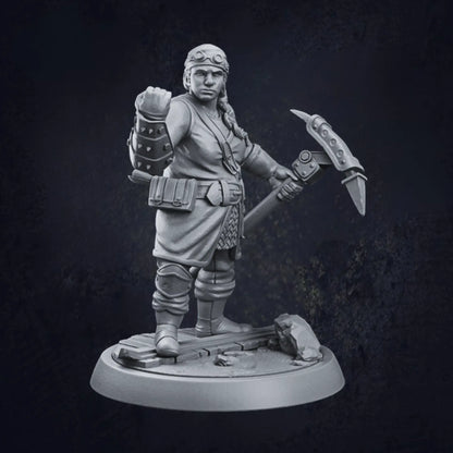 A detailed 3D-printed miniature of a female dwarven artificer, standing on a rocky circular base. The artificer is adorned in a tunic with a belt holding various pouches, paired with armored gauntlets and boots. She wields a large hammer or pickaxe in her right hand, while her left hand is raised in a clenched fist. The model showcases intricate craftsmanship, highlighting the artificer's robust and industrious character.