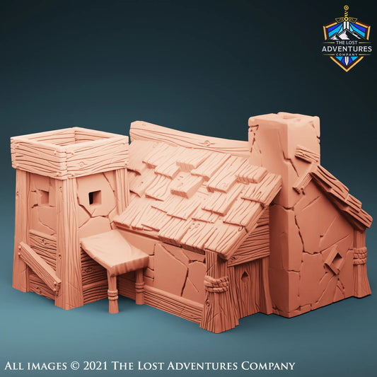 A detailed 3D model of a medieval-style tower house designed for tabletop RPGs. The tower features stone-textured walls with wooden beams, a steeply slanted roof adorned with shingles, and a small chimney. The structure has a square opening at the top, showcasing its playable interior for role-playing game scenarios. The model by The Lost Adventures Company is intricately crafted for fantasy gaming environments.