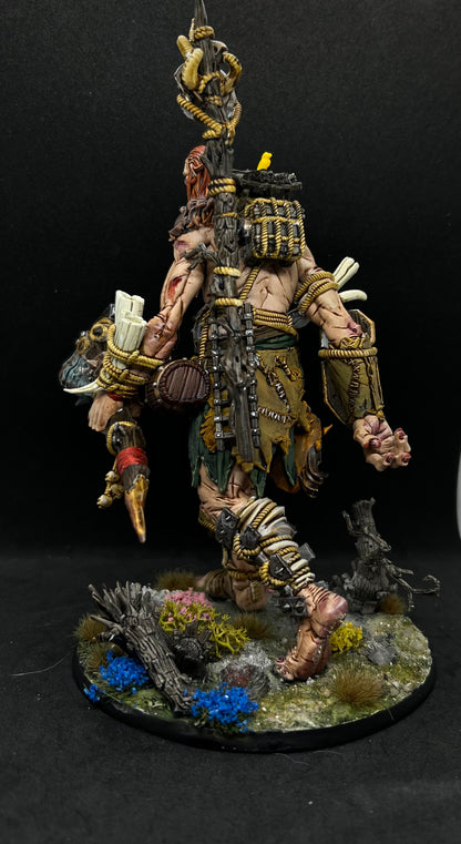 A detailed and intricate model of a fantasy character, possibly a warrior or monster, standing on a base with various accessories and weapons.