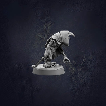 A small, dark-colored figurine of a creature with a hooded head and sharp claws, standing on a base and holding a weapon.