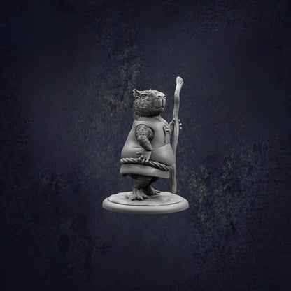 A statue of a bear holding a stick and wearing a vest, standing on a base against a dark background.