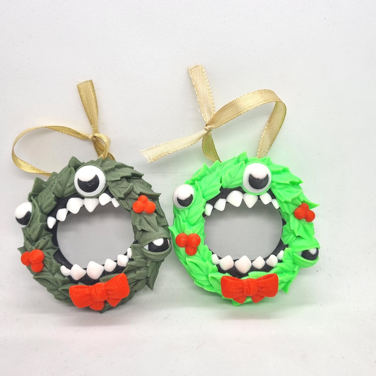 two whimsical wreaths, each with a unique design and color scheme. The wreath on the left is green and has a red bow, while the wreath on the right is green and has a red bow. Both wreaths are adorned with googly eyes and red bows, giving them a playful and festive appearance.