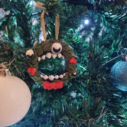 A Christmas tree decorated with ornaments, including a wreath with a monster-like face and a blue ornament.